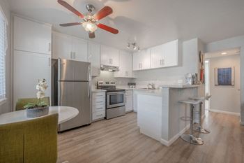 A kitchen with white cabinets and a ceiling fan